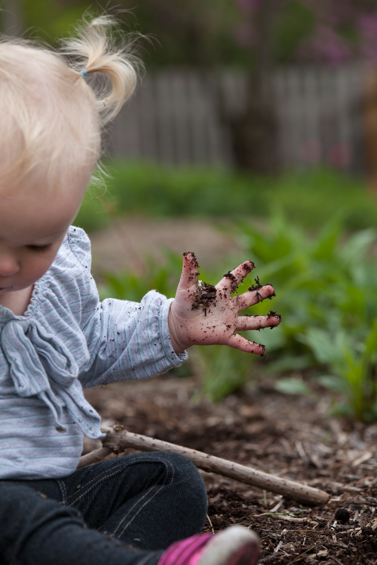 Little girl with blonde playing in dirt.