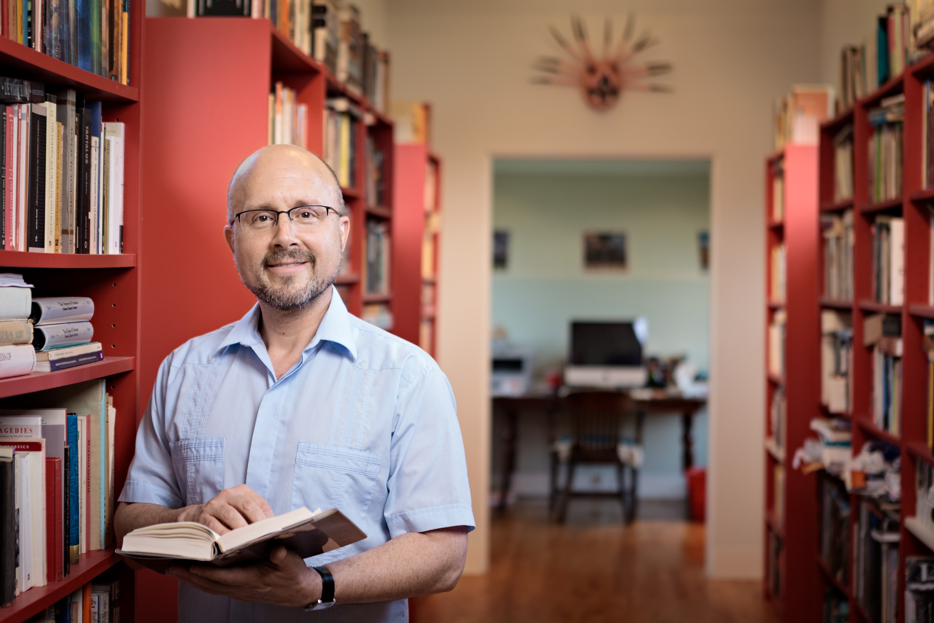 Man with book standing in home library.