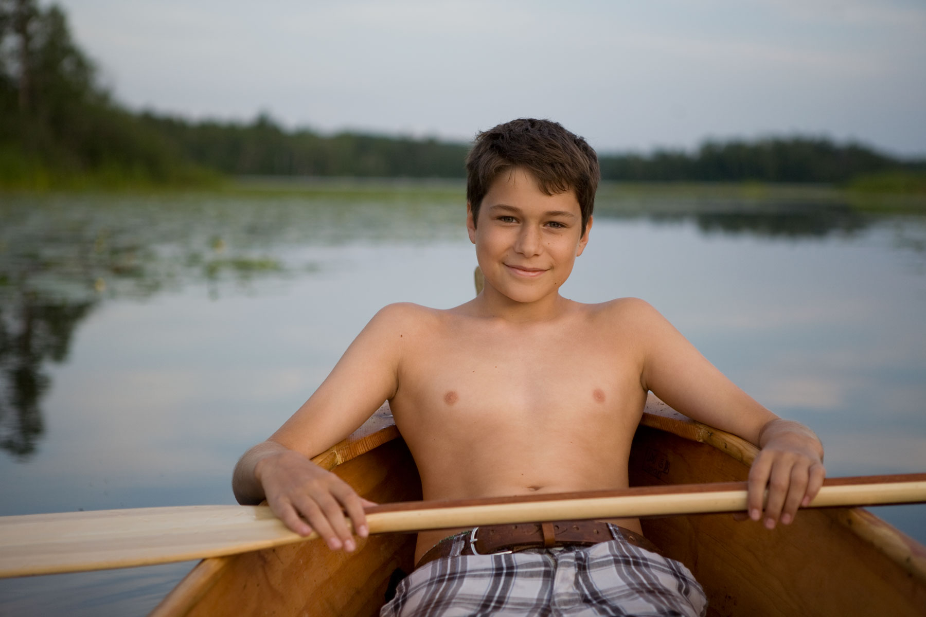 Boy in canoe floating in a lake.