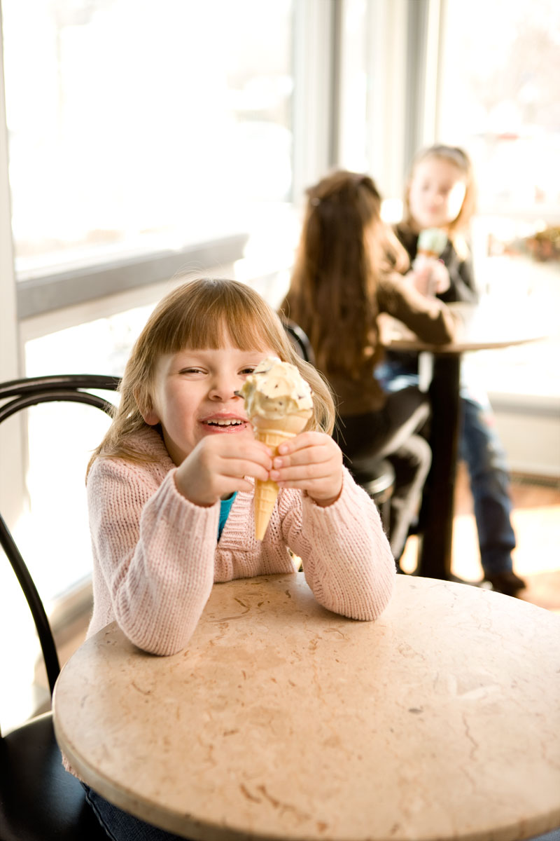 Girl eating ice cream inside ice cream parlor.