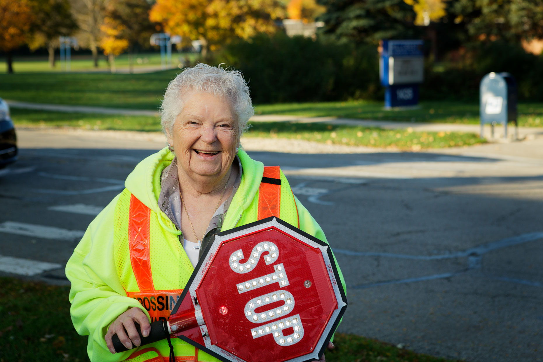 Crossing guard with stop sign standing outside in residential neighborhood.